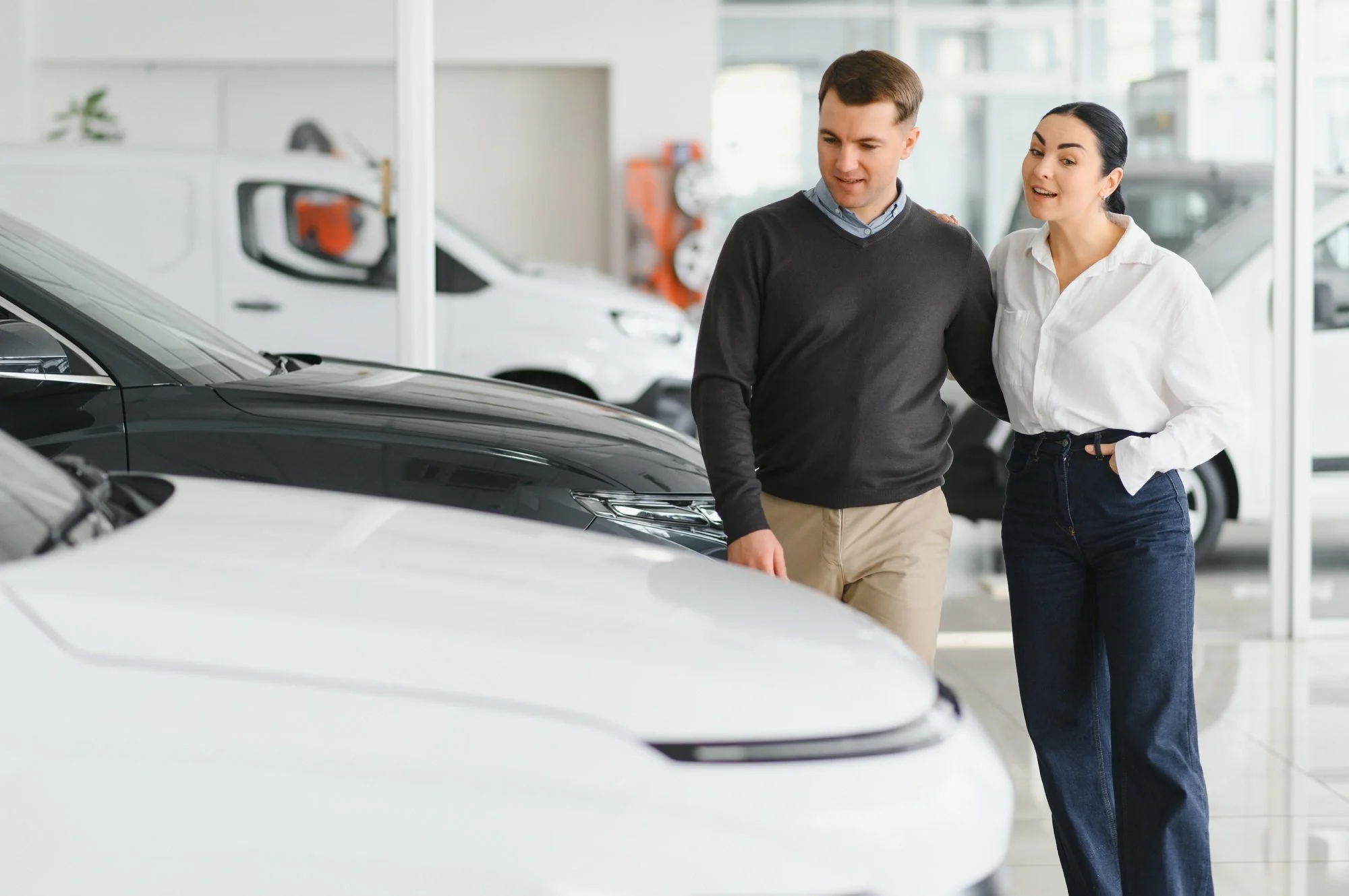 Couple checking new luxury cars at dealership automobile salon